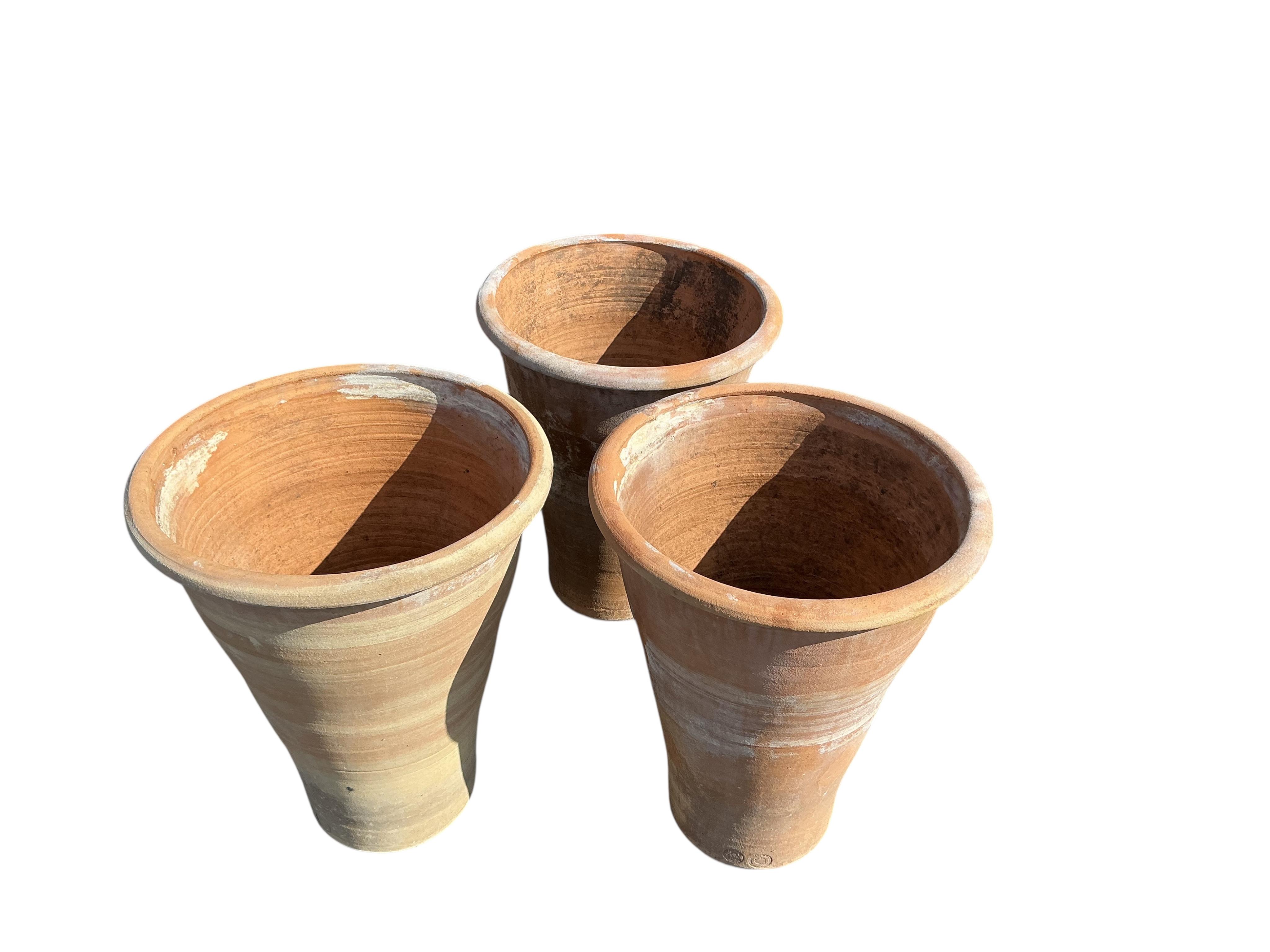 A set of three circular terracotta garden planters, diameter 50cm, height 61cm
